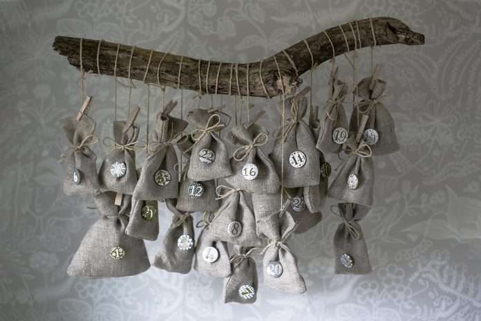 Homemade Christmas calendar Scandinavian style. Small linen bags hanging on a branch.