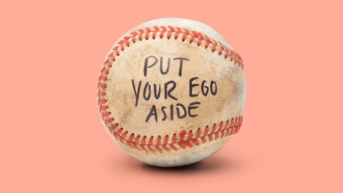 baseball on light red background. on the ball it reads, "put your ego aside"