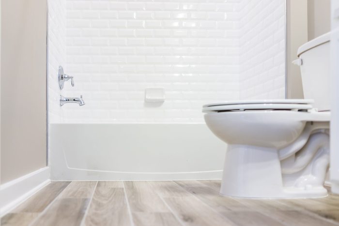 Modern white plain clean toilet bathroom with shower tiles and hardwood floors from ground level