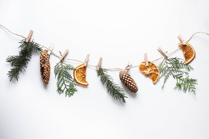 Christmas composition. Christmas garland made of tree branches, cones, dried orange slices and thuja branches on white background. Flat lay, top view, copy space.