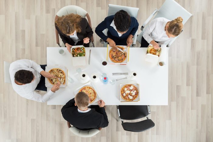 High Angle View Of Business Colleagues Eating Food Together In Office