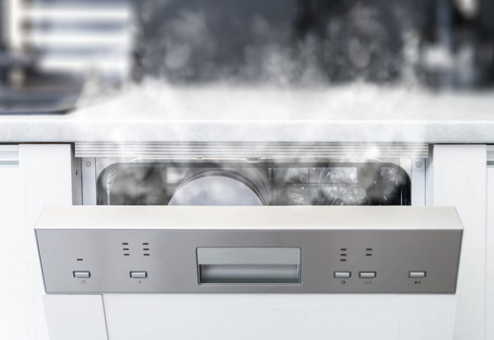 Open dishwasher with steam and clean dishes after washing