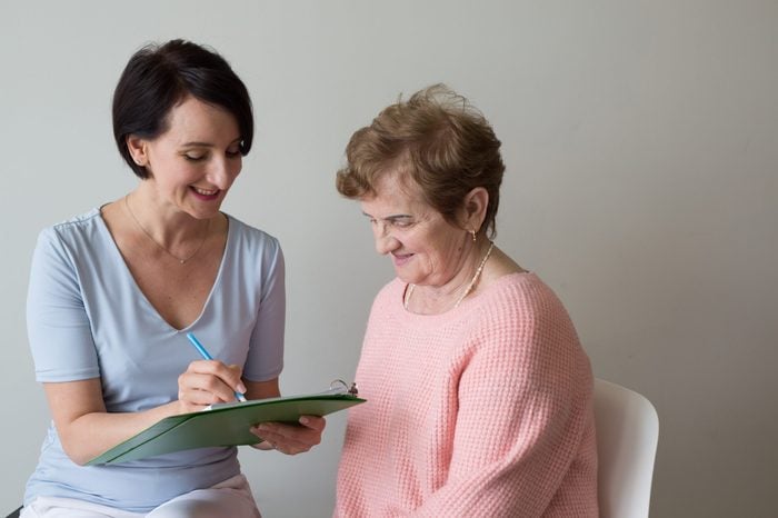 Young woman asking questions elderly female client survey 
