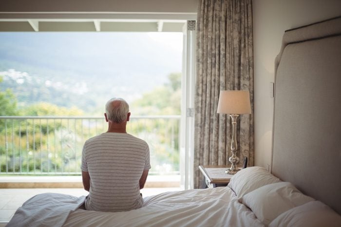 Senior man in bedroom looking at the view through the window