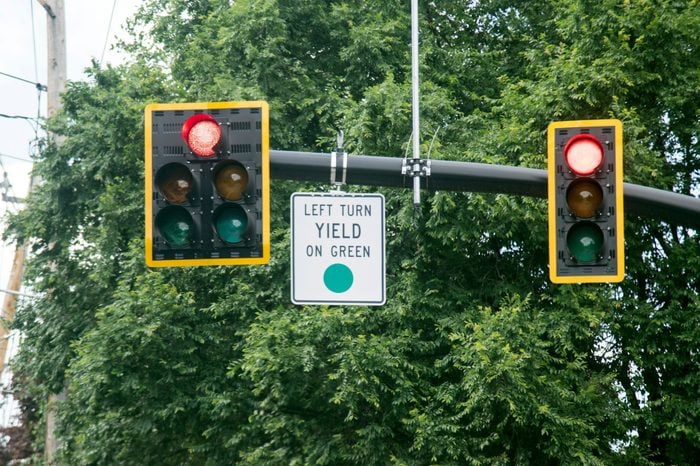 Left Turn Yield On Green Sign attached to a traffic light pole made in white black and green color