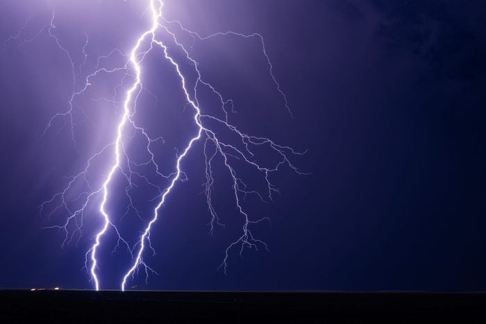 Lightning bolts strike from a storm with a night sky background.