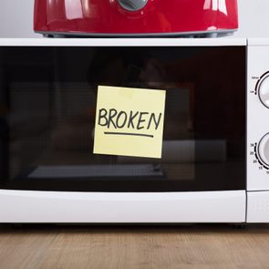 Close-up Of A Microwave Oven With Adhesive Notes Showing Broken Text
