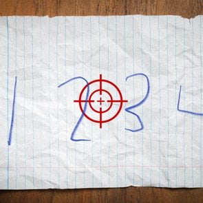 numbers 1, 2, 3, and 4 written in childs handwriting on a piece of loose leaf on a desk. in the center of the page is gun crosshairs