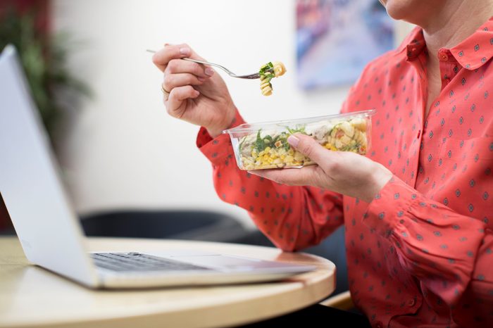 Female Worker In Office Having Healthy Pasta Lunch At Desk