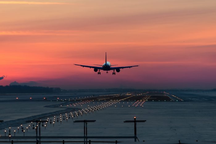 passenger plane is landing in the airport runway at early morning at sunrise time in the frosty winter air