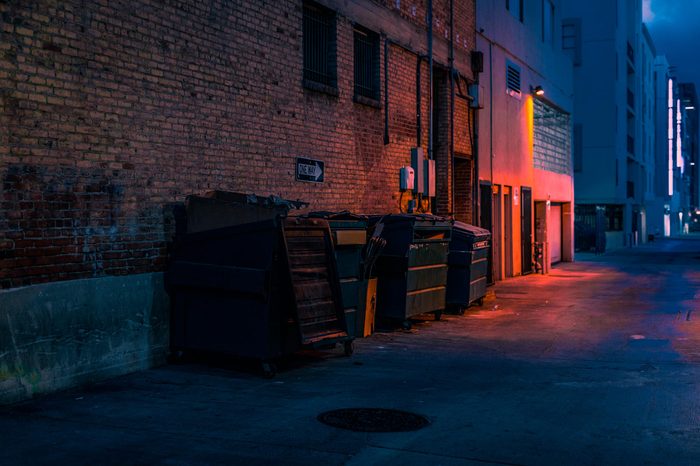 dark empty alley with trash dumpsters. red glowing light.