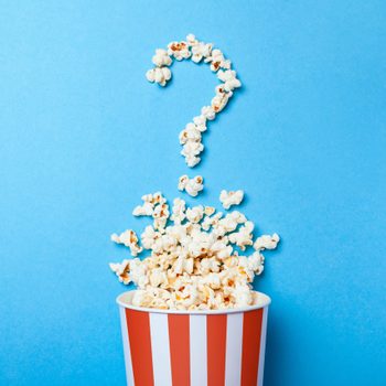 movie popcorn in shape of a question mark against a light blue background