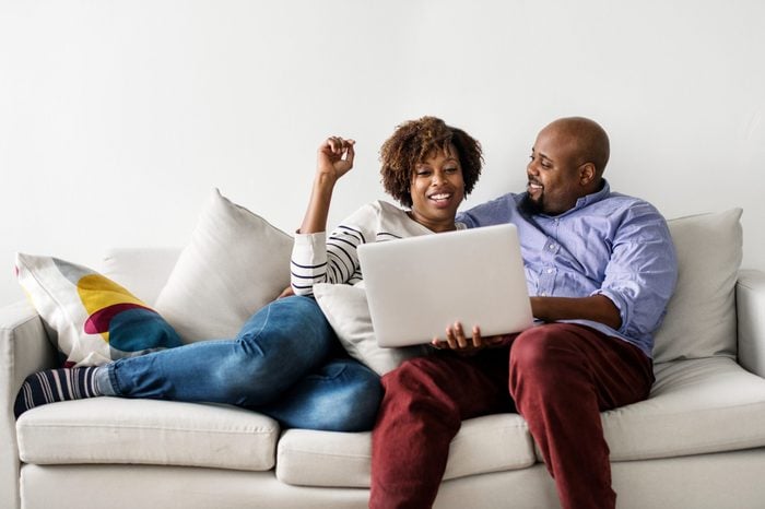 Couple using laptop together on the couch