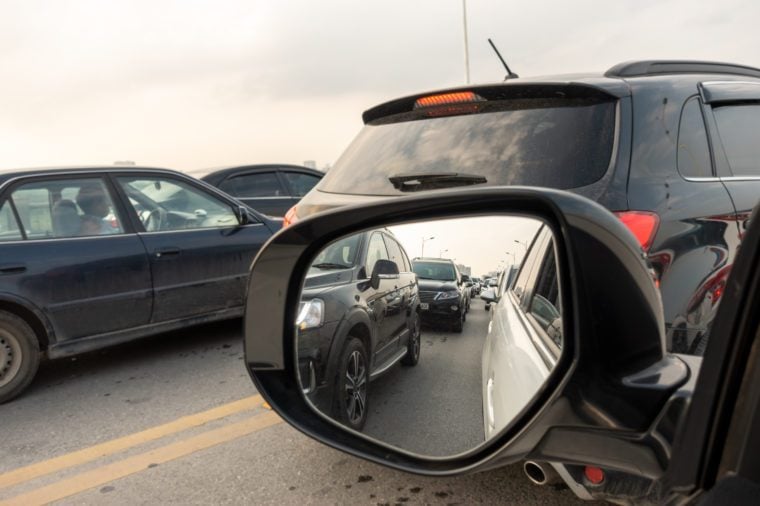 Reflection of traffic flow in left side rear view mirror at rush hour