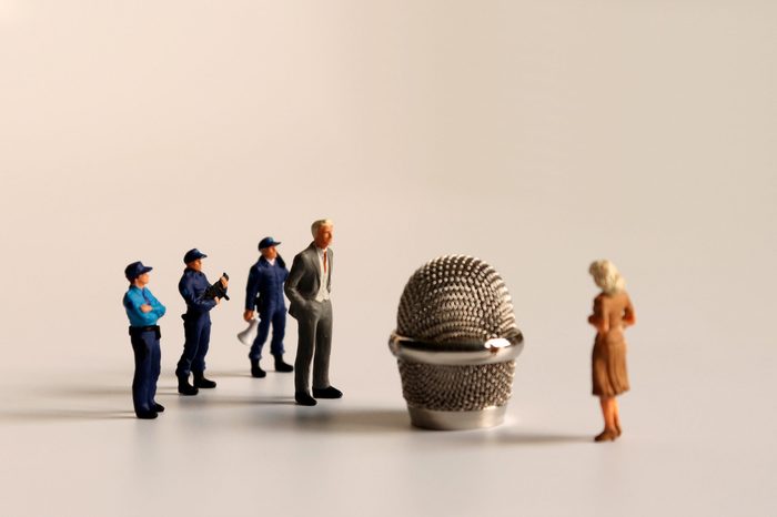 Miniature people standing around a microphone head