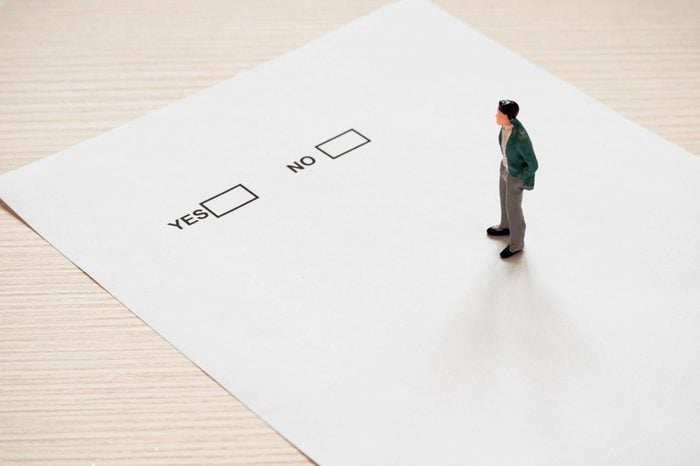 miniature buisenessman standing on paper sheet with yes or no note