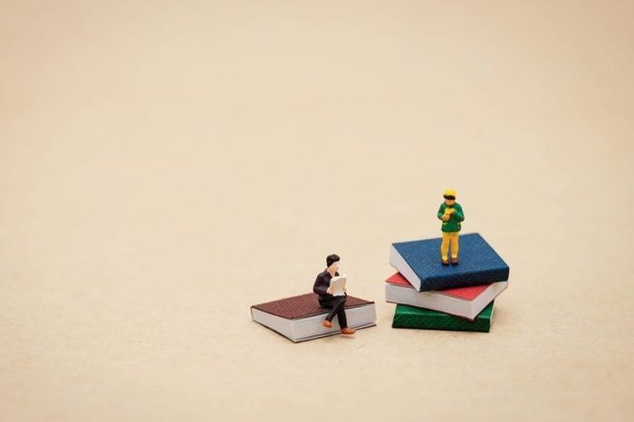 miniature people sitting on small stacks of books