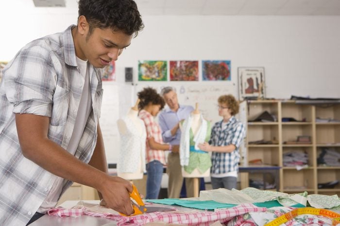 Serious student cutting fabric in home economics classroom