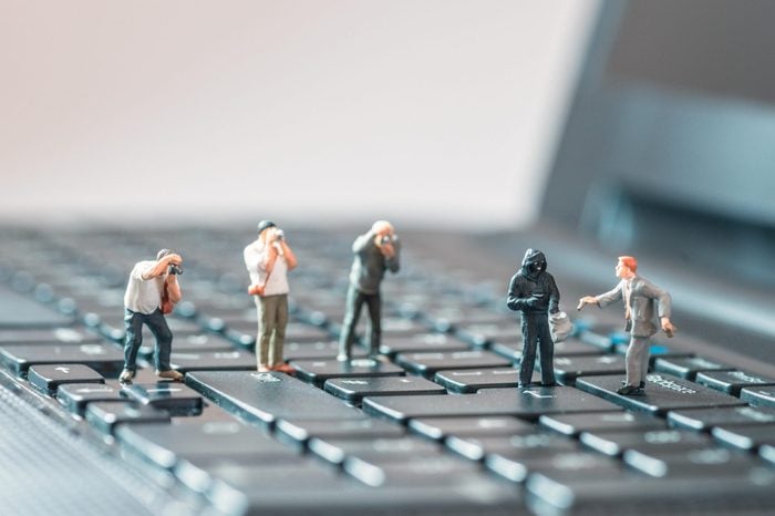 miniature people robbing a business man macro photo on laptop keyboard