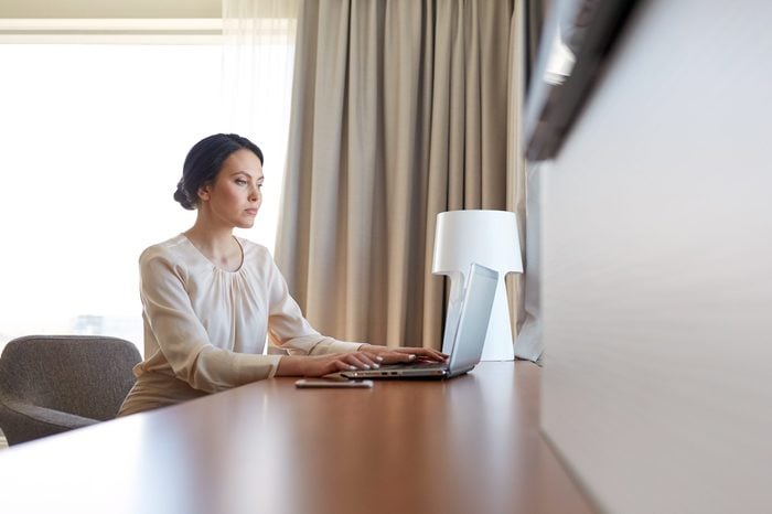 business, people and technology concept - businesswoman typing on laptop at hotel room