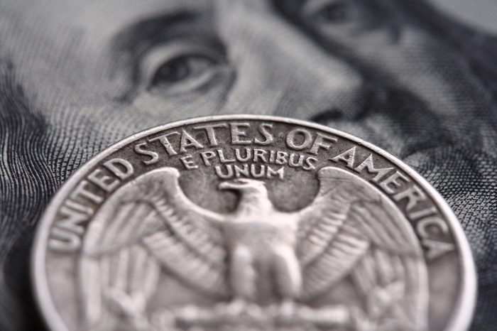 close-up of quarter dollar coin on the one hundred Dollar bill