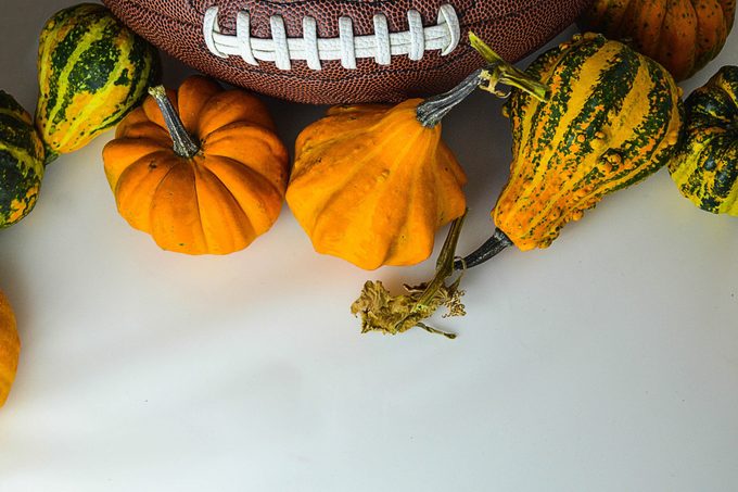 The ball for football with pumpkins on the white background. The picture is awesome for fall football game invitation card.