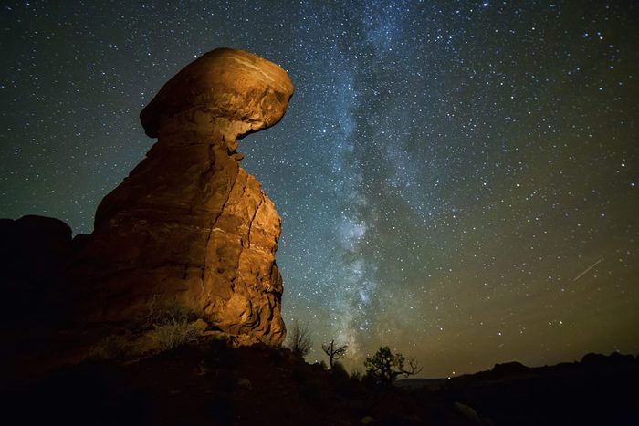 Night shot of Balanced Rock at Arches National Park in Utah, with the Milky Way visible in the dark sky.