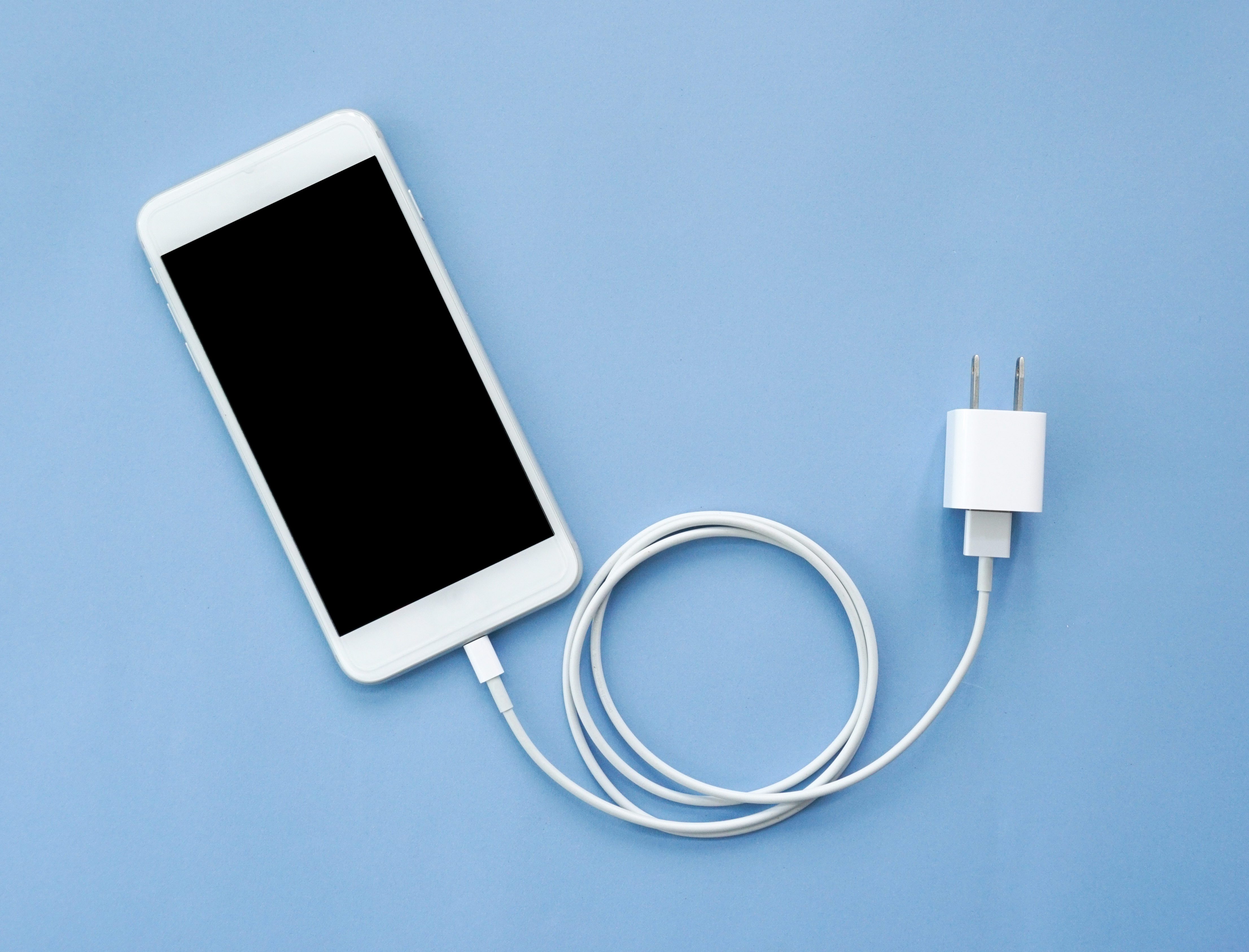 Smartphone Plug In with Charger Adapter on Blue Background Top View