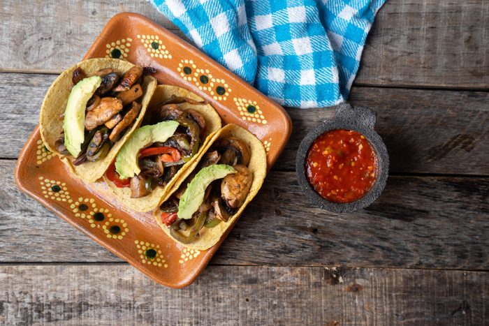 Mexican vegan tacos with avocado and mushrooms on wooden background