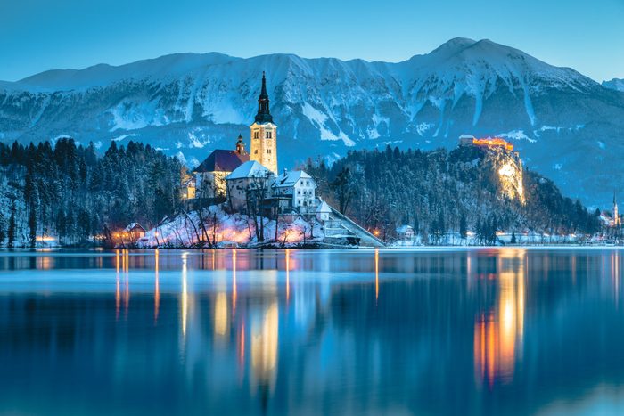 Beautiful twilight view of Lake Bled with famous Bled Island and historic Bled Castle in the background during scenic blue hour at dawn in winter, Slovenia
