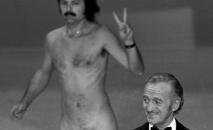 Mandatory Credit: Photo by Anonymous/AP/Shutterstock (6594477a) Actor David Niven presents an award as streaker Robert Ope crosses the stage during the 1974 Academy Awards show in Los Angeles Film Five Most, LOS ANGELES, USA