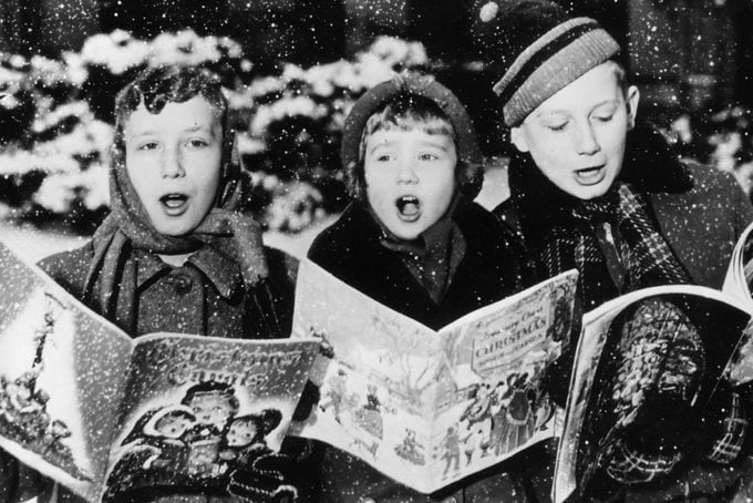 three children singing christmas carols in the snow
