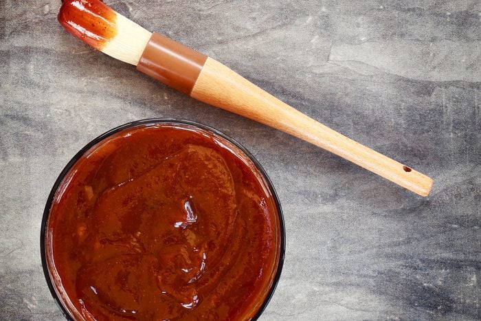 Barbecue sauce with basting brush over stone table with room for copy space. 