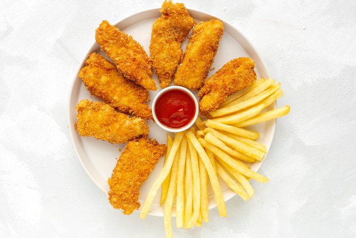Homemade chicken nuggets battered with panko and French fries views from above on white background. American food