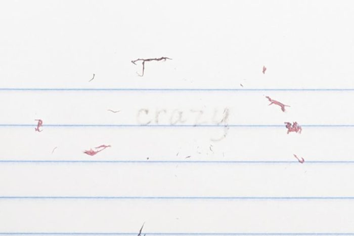 erased text "crazy" with eraser shavings on loose leaf paper