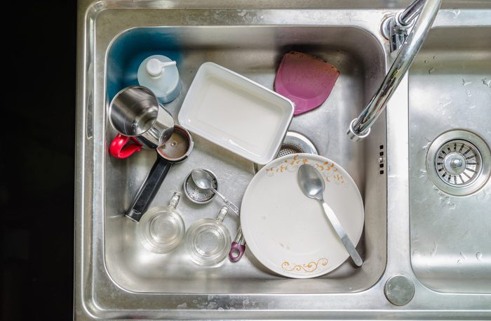 Unwashed dishes and utensils in a kitchen sink