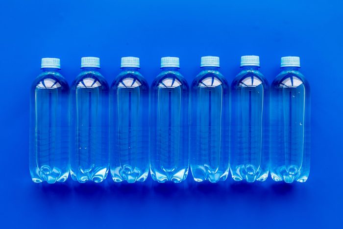 Plastic bottles with pure water on blue background top view
