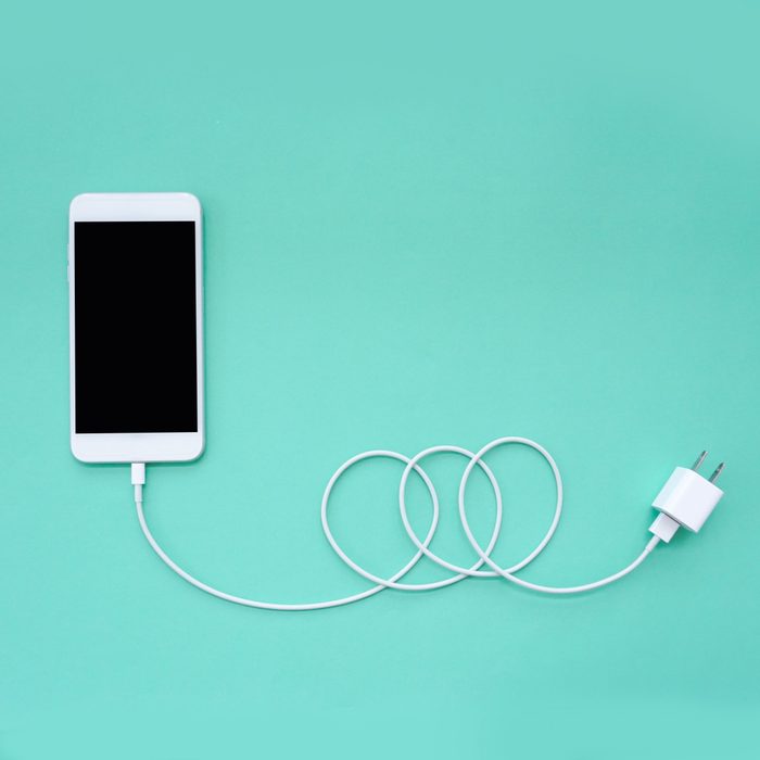 Smartphone Connects to Charger through USB Cable on Turquoise Background Top View; Shutterstock ID 1073489141