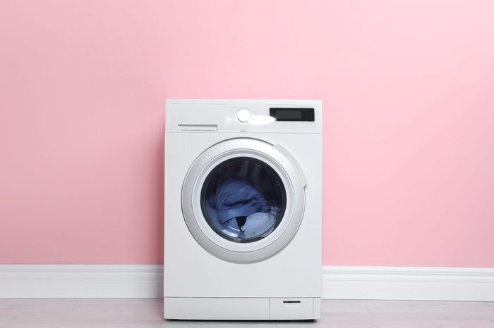Washing machine with laundry near color wall. Space for text