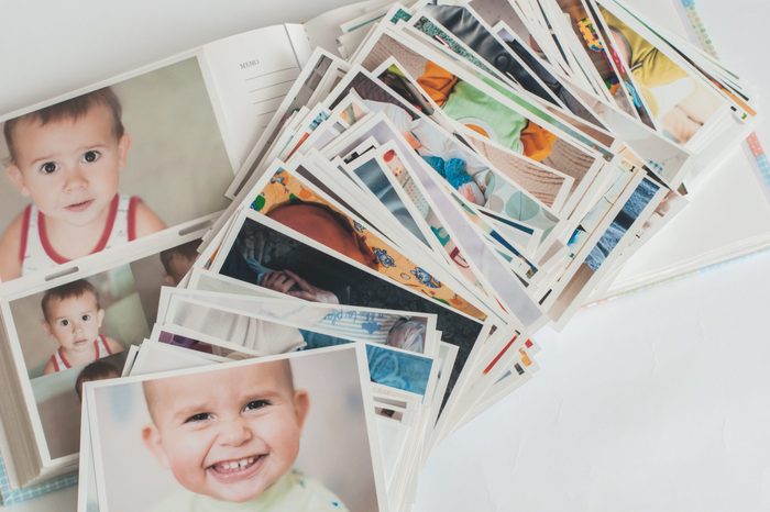 Pile of printed photographs in disorder on a photo album with pictures.