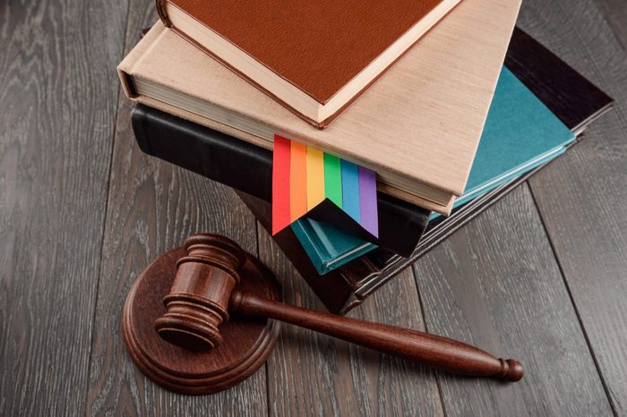 Judge's gavel and books with a gay rainbow bookmark on wood table. LGBT rights, justice and law equality concept.