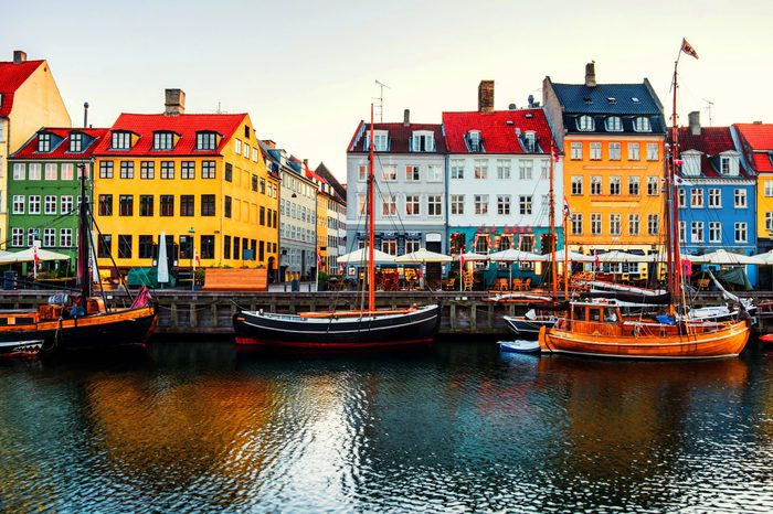 Copenhagen, Denmark. View of famous Nyhavn area in the center of Copenhagen, Denmark in the morning. Boats moored with historical buildings, clear bright sky