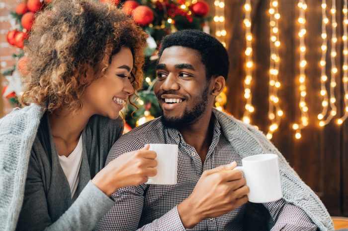 Happy young black couple drinking coffee and enjoying Christmas morning together, copy space