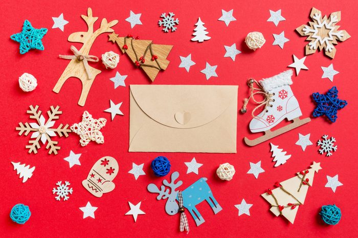 Top view of craft envelope, holiday toys and decorations on red Christmas background. New Year time concept.