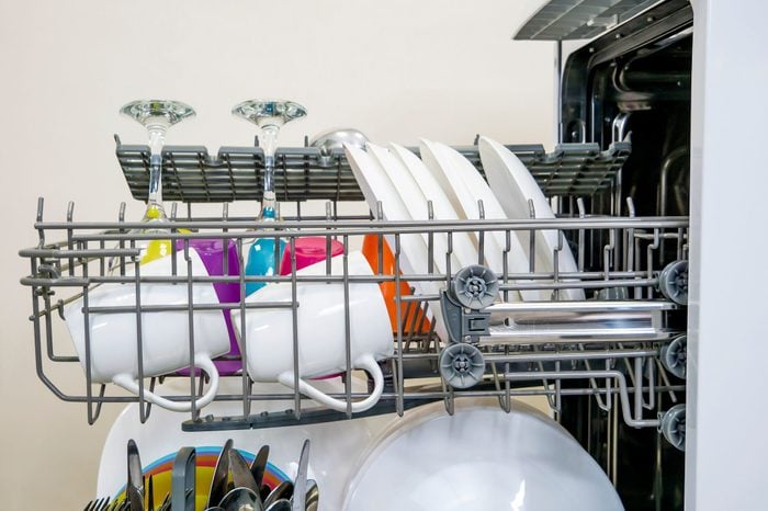 colorful Dishware inside built-in dishwasher, glasses, mugs, plates, wine glasses . Dishwashing machine rack