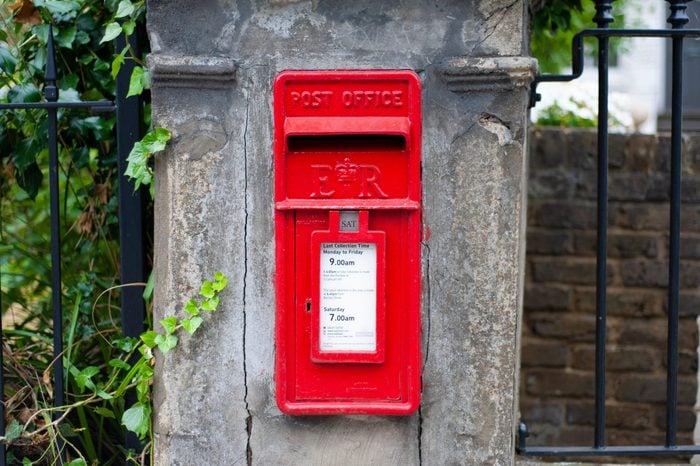 London - United Kingdom - 20 July 2018 - Traditional old English red postbox mounted in a cotswold stone wall.