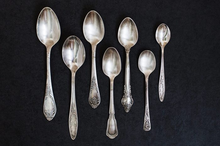 Silver spoons on the grey stone background.