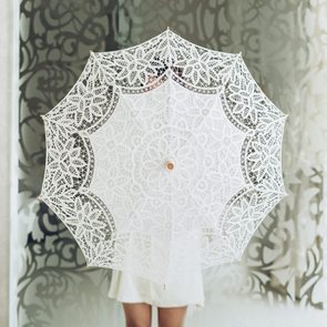 White fabric umbrella in hands. Studio photo
