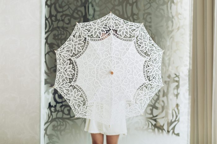 White fabric umbrella in hands. Studio photo