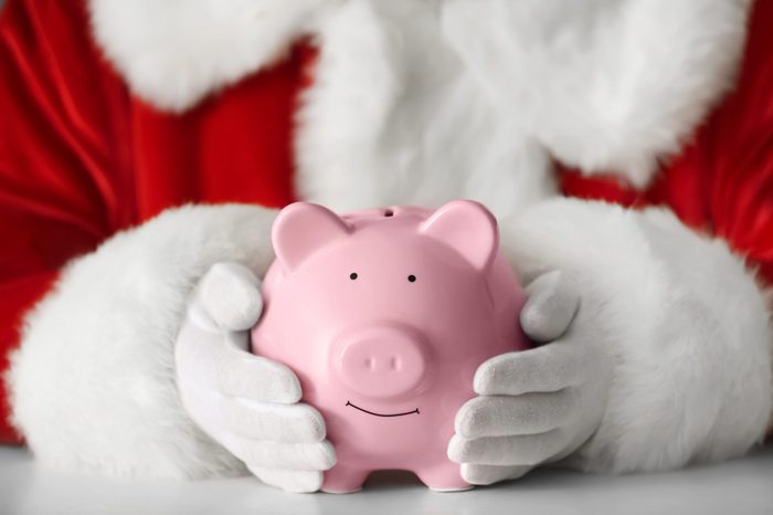 Santa Claus holding piggy bank at table